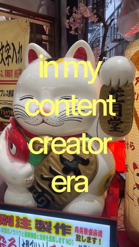 Gato de la suerte en una calle de Japón, sobre la foto: «in my content creator era»